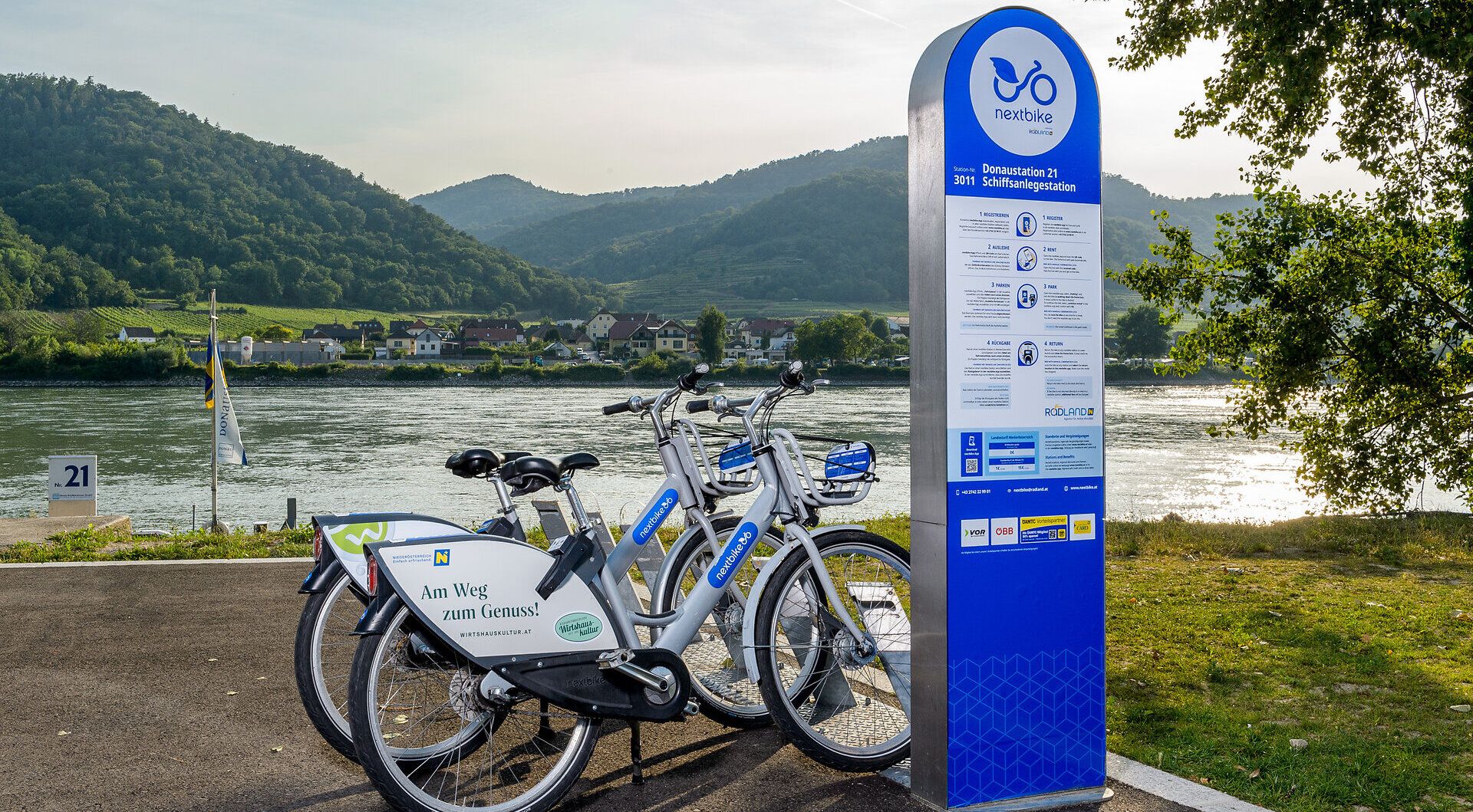 Entlang der sanften Wellen der Donau stehen Fahrräder bereit, um die malerische Landschaft zu erkunden. Die umliegenden Hügel laden dazu ein, die Schönheit der Natur zu genießen und die frische Luft zu atmen. Ein idealer Ort, um die Wirtshauskultur Niederösterreichs zu erleben und die Seele baumeln zu lassen.