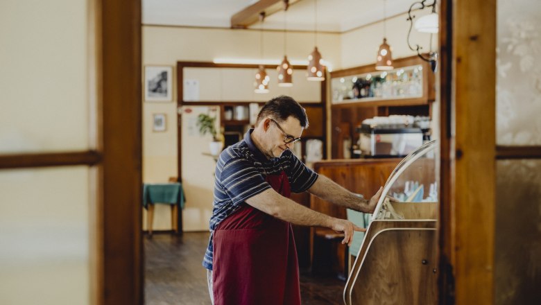 A man in a cozy living room operates a jukebox.