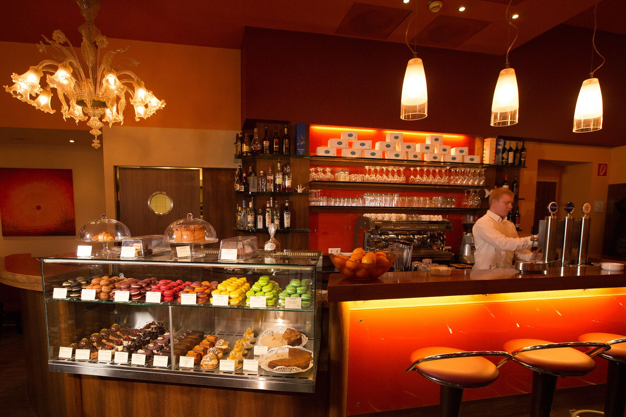 Innenansicht eines Cafés mit Theke, Barhocker und Gebäckvitrine.