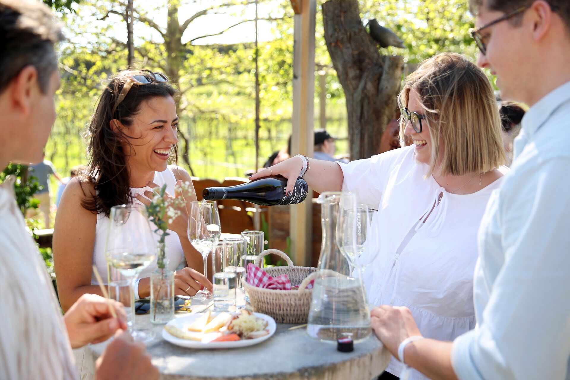 Junge Frau schenkt ein Glas Wein nach.