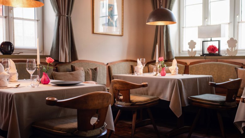 Cozy dining room with laid tables, candles and flowers decorated in pastel shades.
