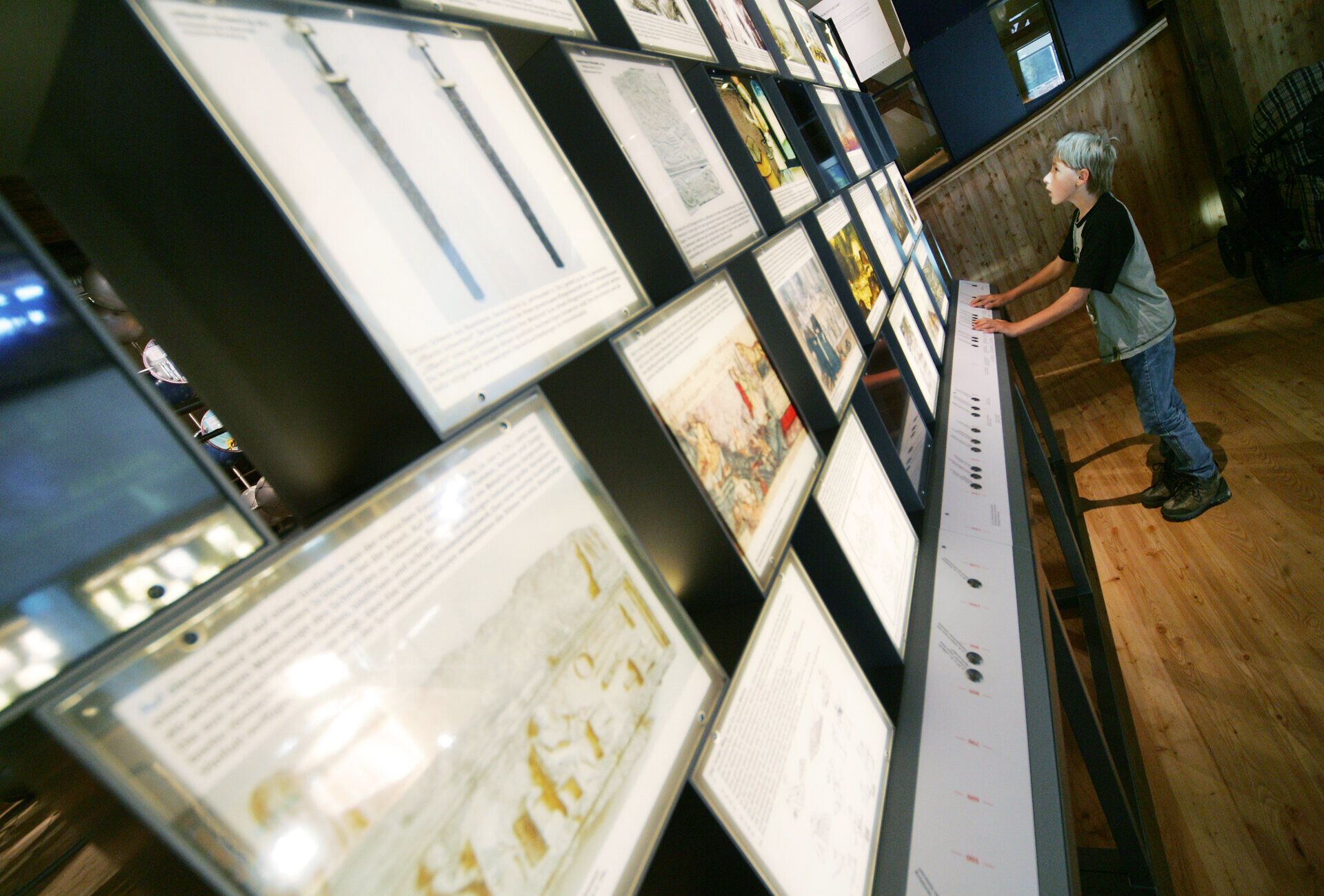 In der faszinierenden Welt des Eisens erleben Besucher die Kunst des Schmiedens hautnah. Ein neugieriger Junge betrachtet die beeindruckenden Exponate, die die Geschichte und Tradition des Handwerks lebendig werden lassen. Die Atmosphäre ist geprägt von der Leidenschaft für das Handwerk und der Schönheit der metallenen Kunstwerke.