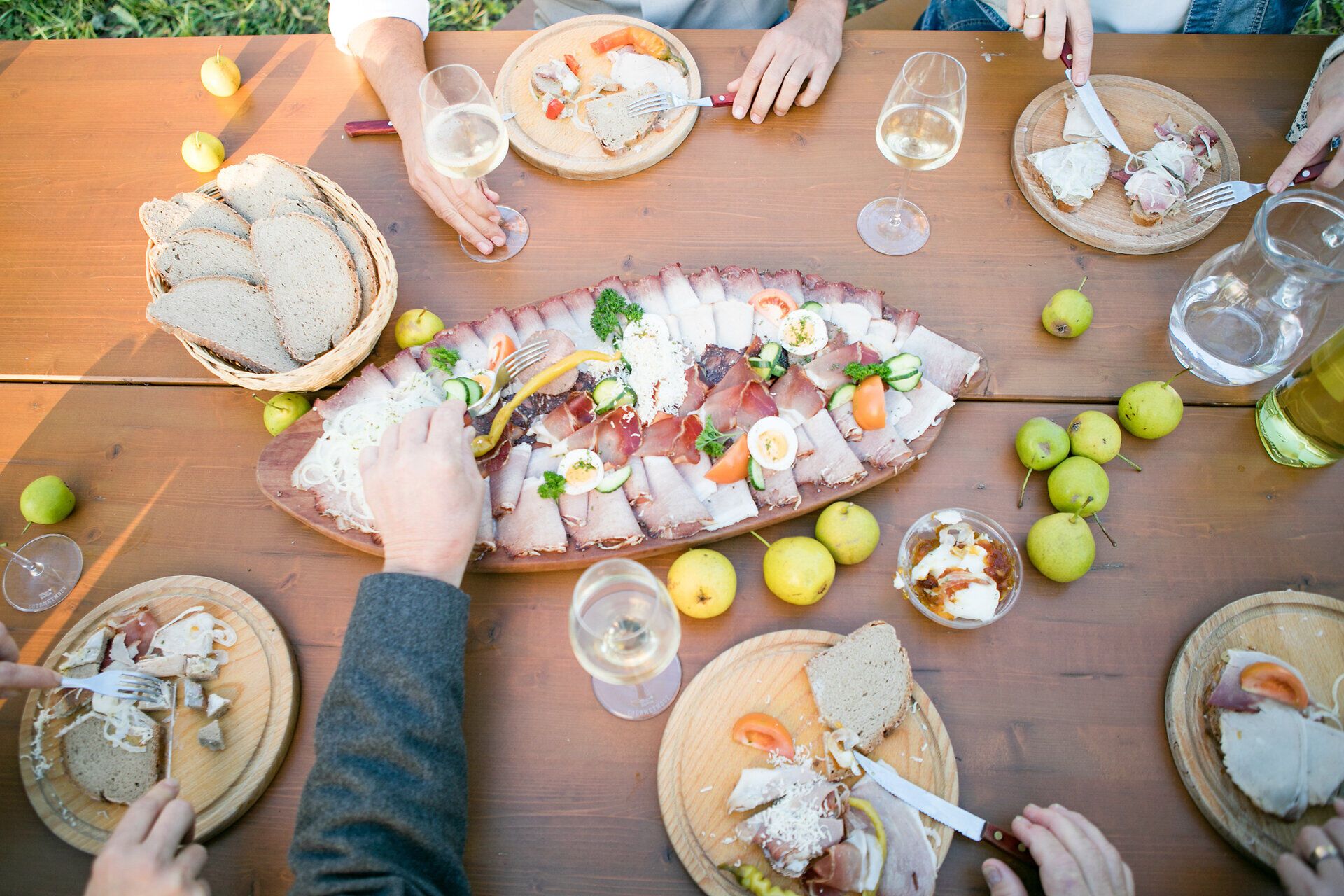 In der goldenen Herbstsonne versammeln sich Freunde um einen reich gedeckten Tisch, der mit köstlichen Spezialitäten und frischen Birnen aus der Region geschmückt ist. Die Atmosphäre ist geprägt von fröhlichem Lachen und dem Genuss der Erntezeit, während die bunten Blätter der Bäume im Hintergrund sanft im Wind wehen.
