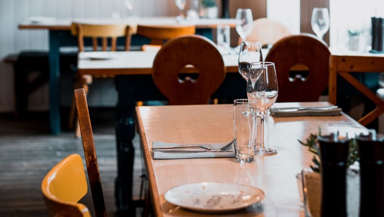 A table set in a cozy restaurant with wooden furniture and wine glasses.