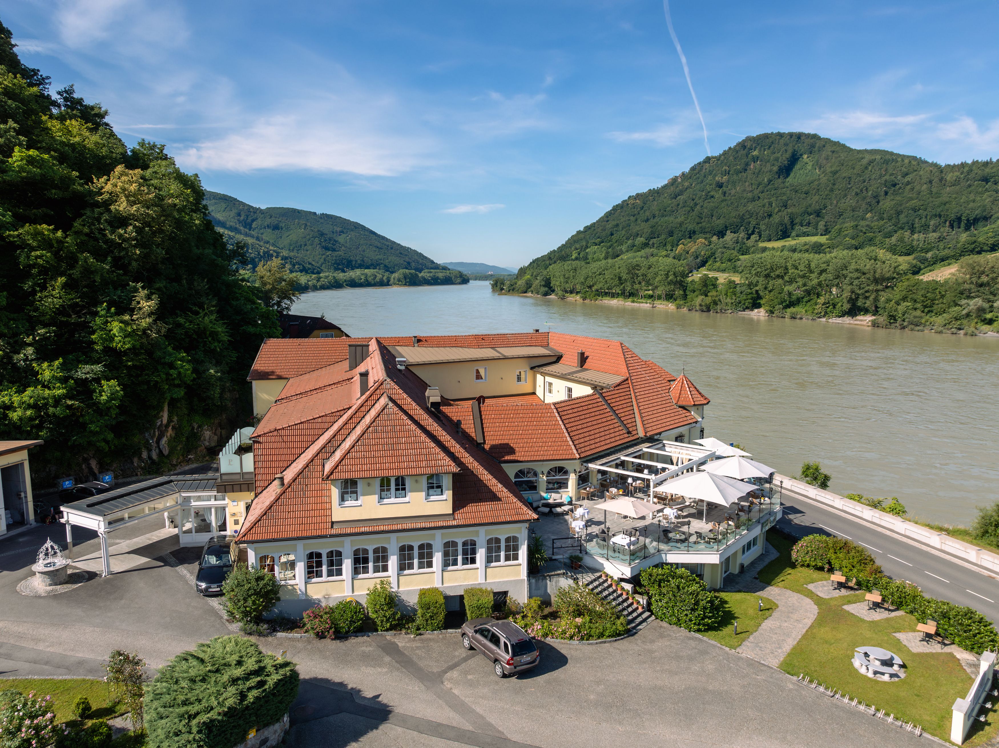 Hotel ResidenzWachau am Flussufer mit umliegenden Hügeln.