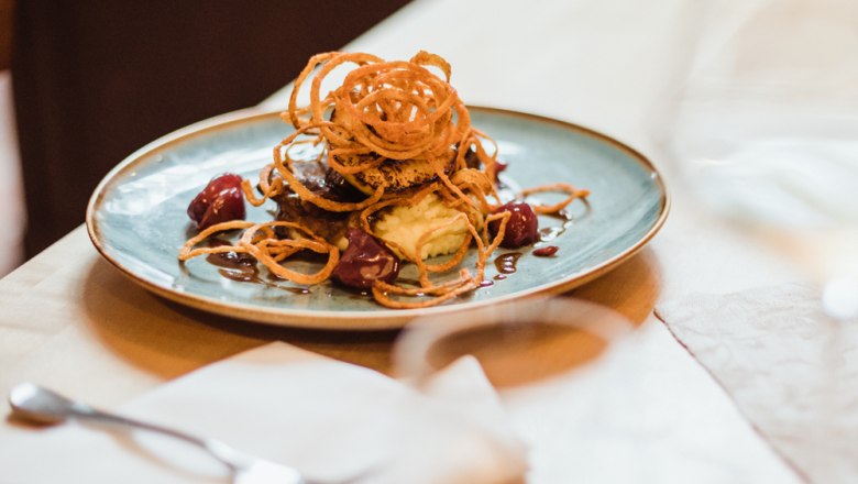 Fleischgericht mit Zwiebelringen auf Kartoffelp&uuml;ree und Sauce.