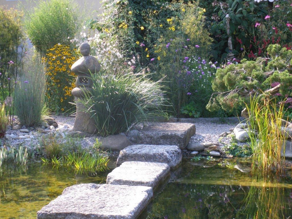 Ein Schaugarten mit Steinlaterne, Blumen und Teich.