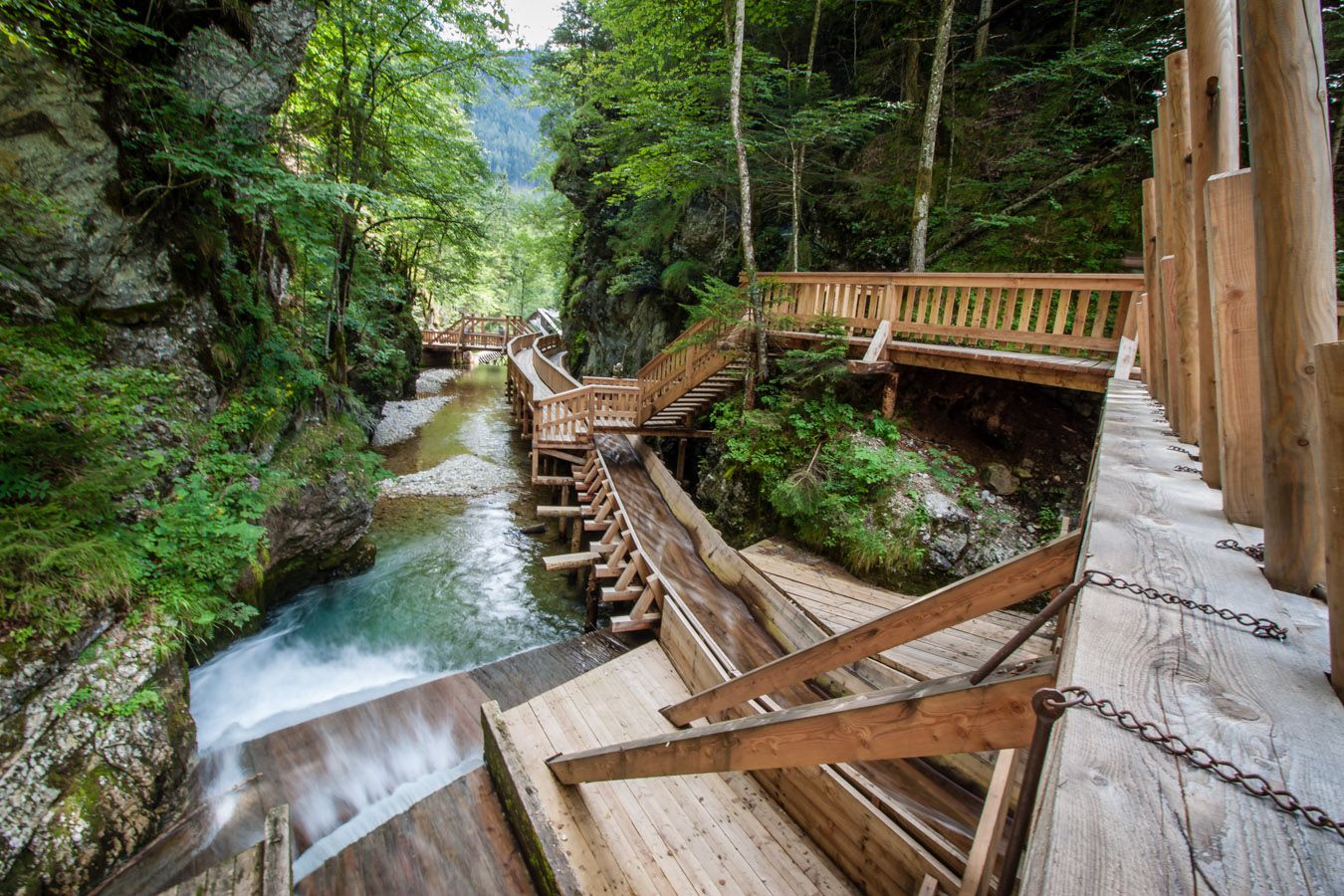 Holzstege im Mendlingtal entlang eines Baches in einer bewaldeten Schlucht.