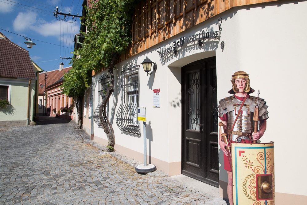 Ein Pappaufsteller eines römischen Soldaten steht vor einem Gebäude in Traismauer.