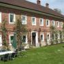 Brick building with garden furniture and parasol on lawn.