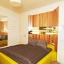 Modern furnished bedroom with yellow bed and wood paneling on the wall.