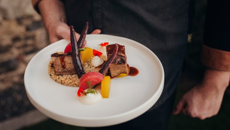 Ein Teller mit geschmortem Fleisch, Einkornrisotto, Erdäpfelschaum und Rüben-Variation.