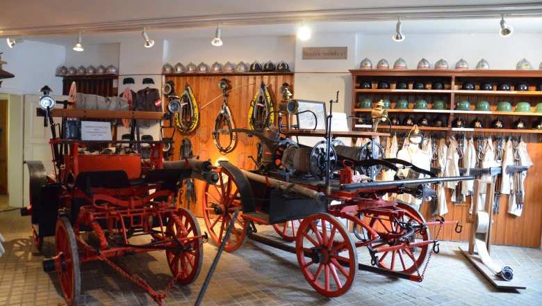 Interior view of the St. Leonhard am Forst Fire Brigade Museum with old firefighting equipment and helmets.