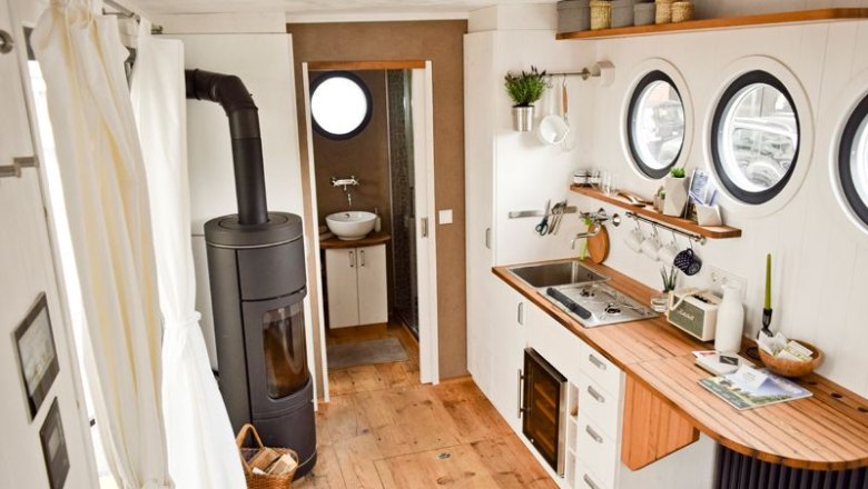 Interior view of a caravan with kitchen, wood-burning stove and bathroom.