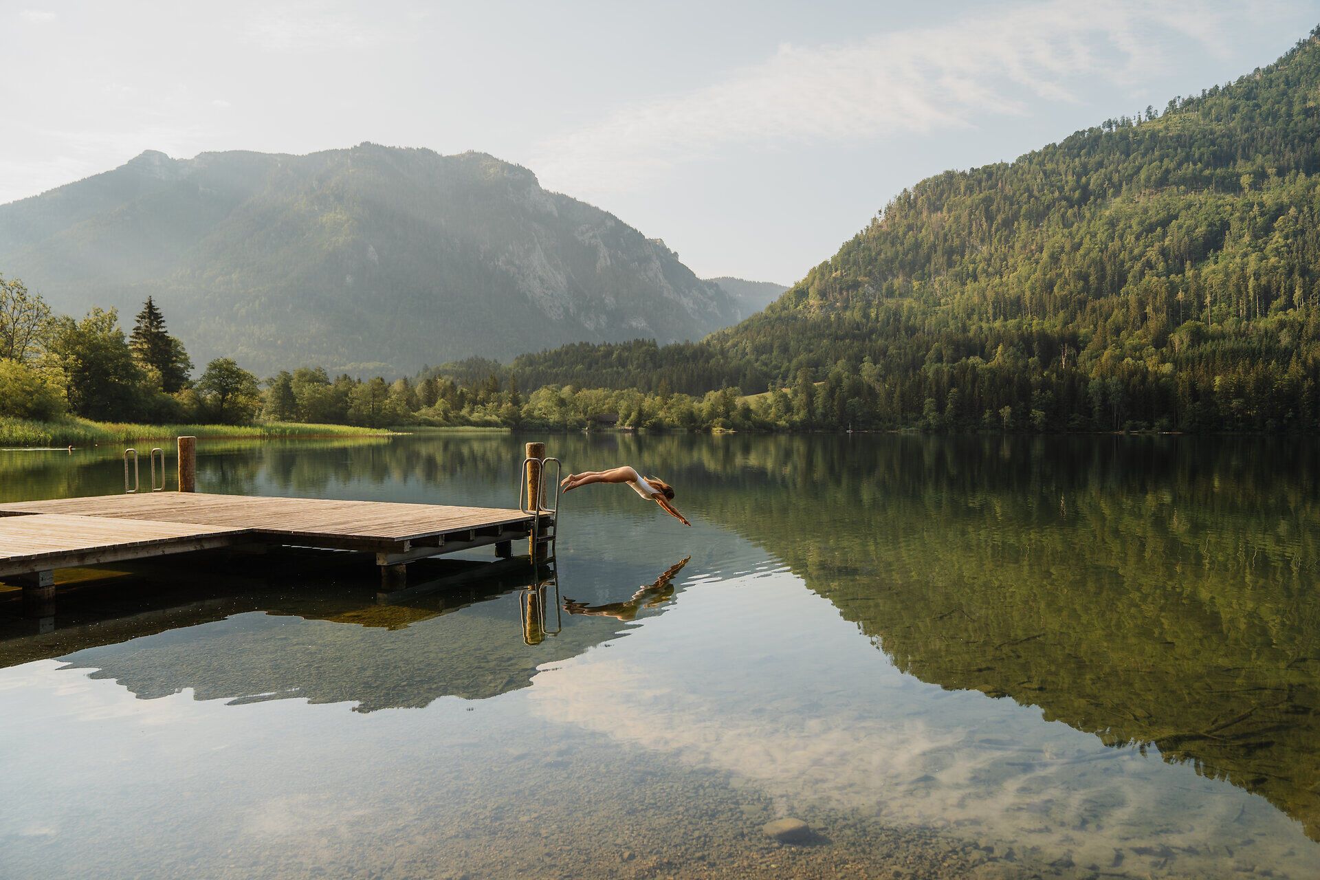 Ein mutiger Sprung ins erfrischende Wasser verspricht unvergessliche Momente inmitten der beeindruckenden Berglandschaft. Die ruhige Oberfläche des Sees spiegelt die majestätischen Berge wider und lädt zu einem erholsamen Tag in der Natur ein.