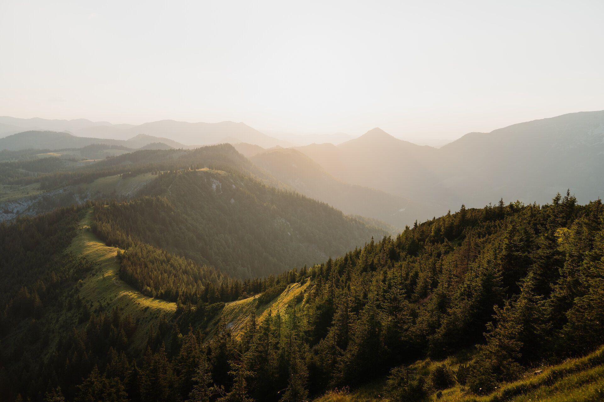 Die sanften Hügel und majestätischen Berge laden zu unvergesslichen Erlebnissen in der Natur ein. Die goldenen Strahlen der Abendsonne tauchen die Landschaft in ein warmes Licht und schaffen eine friedliche Atmosphäre, die Wanderer und Naturliebhaber gleichermaßen begeistert.