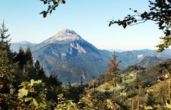 Die majestätischen Gipfel erheben sich stolz über die sanften Hügel, während die Sonne den Himmel in warmen Farben erleuchtet. Ein Gefühl von Freiheit und Abenteuer durchdringt die Luft, während Wanderer die atemberaubende Aussicht genießen und die Ruhe der Natur erleben.