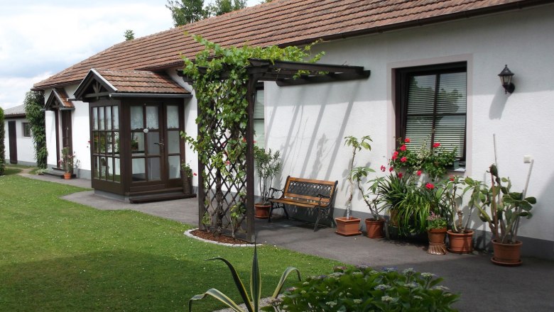 Well-kept garden with many potted plants and the entrance doors to the apartments.