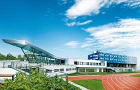 Modernes Sportzentrum mit Laufbahn und blauen Himmel.