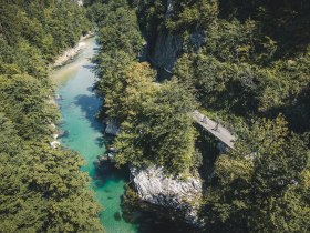 Luftaufnahme der Ybbs, umgeben von bewaldeter Vegetation und daneben zwei Radfahrenden am Ybbstalradweg