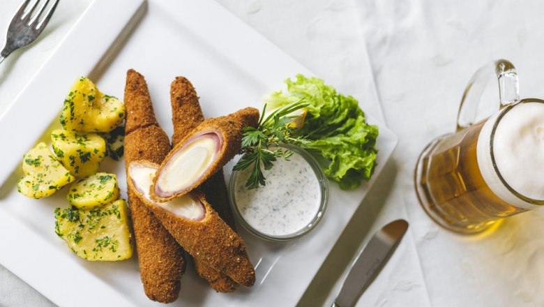 Baked asparagus with potatoes, salad and beer on a white plate.