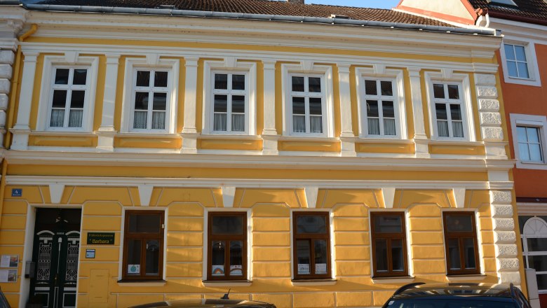 Gelbes Gebäude mit weißen Fensterrahmen und dekorativen Elementen in Pöchlarn.