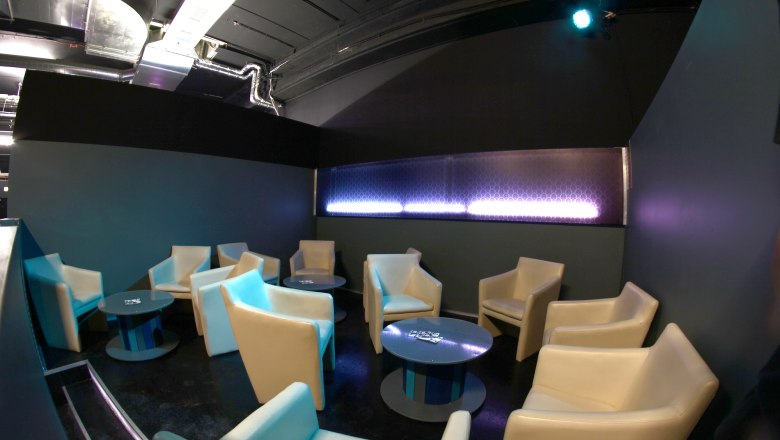 Lounge area with beige armchairs and round tables in a modern room.