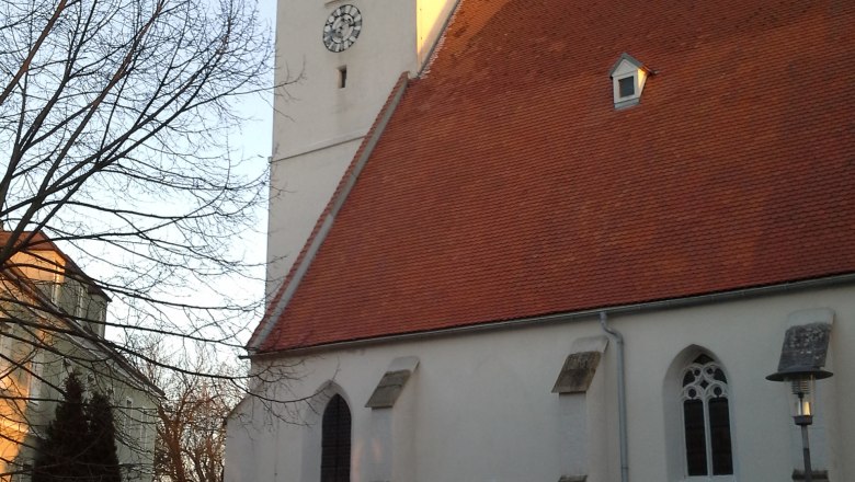 Kirche mit rotem Dach und Uhrturm in Kapelln bei Sonnenuntergang.
