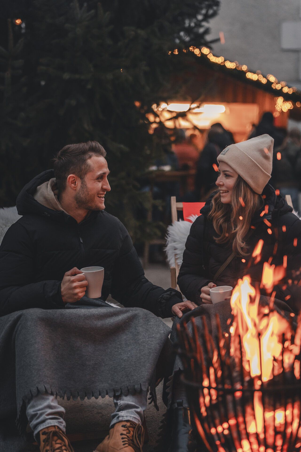 Pärchen genießt Heißgetränk vor dem lodernden Feuerkorb.