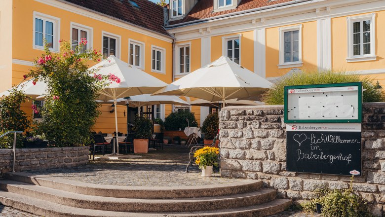 Historic house from the 14th century., © Niederösterreich Werbung/Daniela Führer Yellow historic building with terrace and parasols, surrounded by plants.