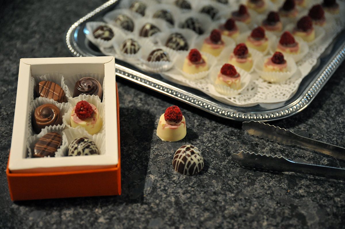 Eine Schachtel Pralinen und ein Tablett mit Pralinen auf einem Tisch.