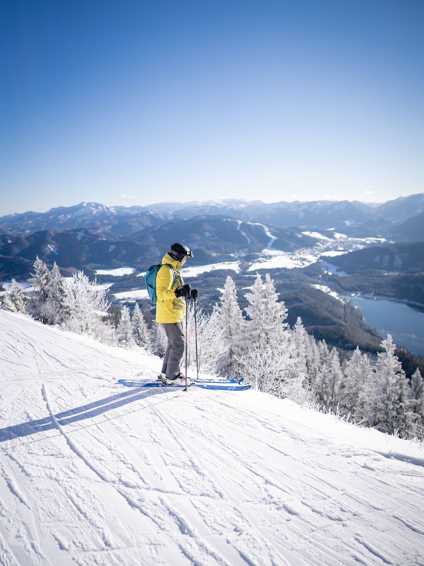 Die strahlende Wintersonne taucht die schneebedeckte Landschaft in ein warmes Licht, während ein Skifahrer die sanften Hänge hinuntergleitet. Umgeben von majestätischen Bergen und glitzernden Tannen, bietet dieser Ort ein unvergessliches Erlebnis für Wintersportliebhaber.
