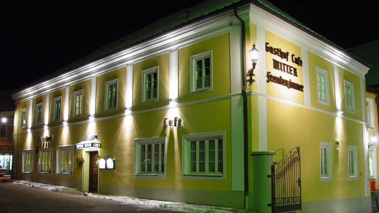 Nachtaufnahme eines gelben Gebäudes mit der Aufschrift 'Gasthof Café Mitter'.