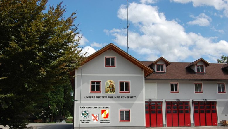 Feuerwehrgebäude mit roten Toren und Schriftzug 'Unsere Freizeit für Ihre Sicherheit'.