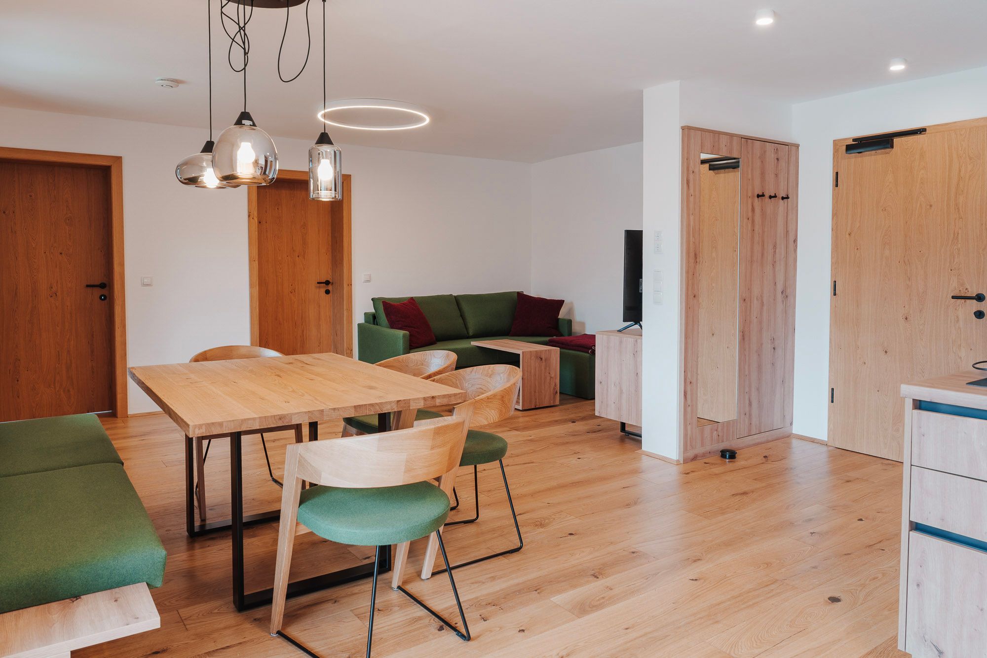 Modern eingerichtetes Wohn- Esszimmer mit Holzmöbeln und grünen Akzenten.