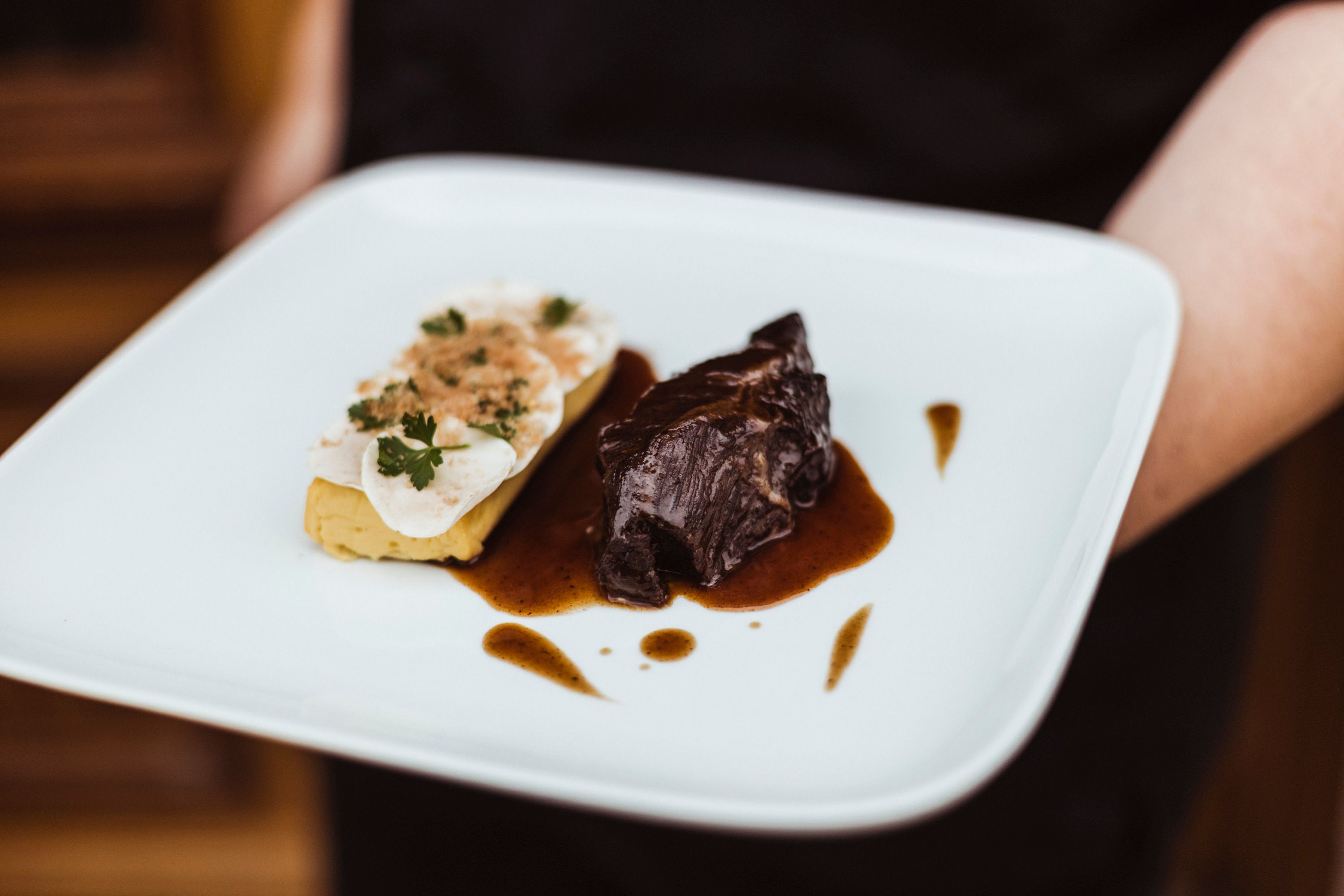 Ein Teller mit Rindsbackerl in Sauce und Champignons auf Erdäpfel-Soufflé.