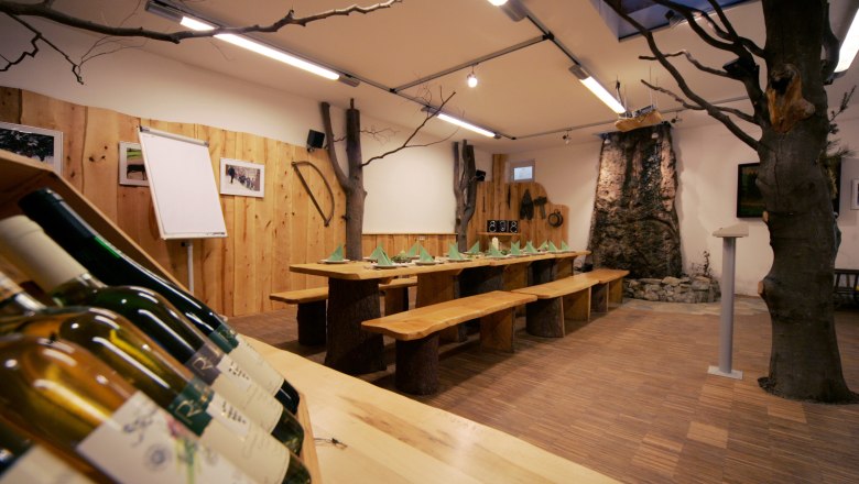 Gem&uuml;tliches Naturparkhaus mit Holztisch, einem Baum im Zimmer und warmem Holzinterieur.