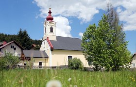 Kirche in Mitterbach mit rotem Turm und grünem Baum im Vordergrund.