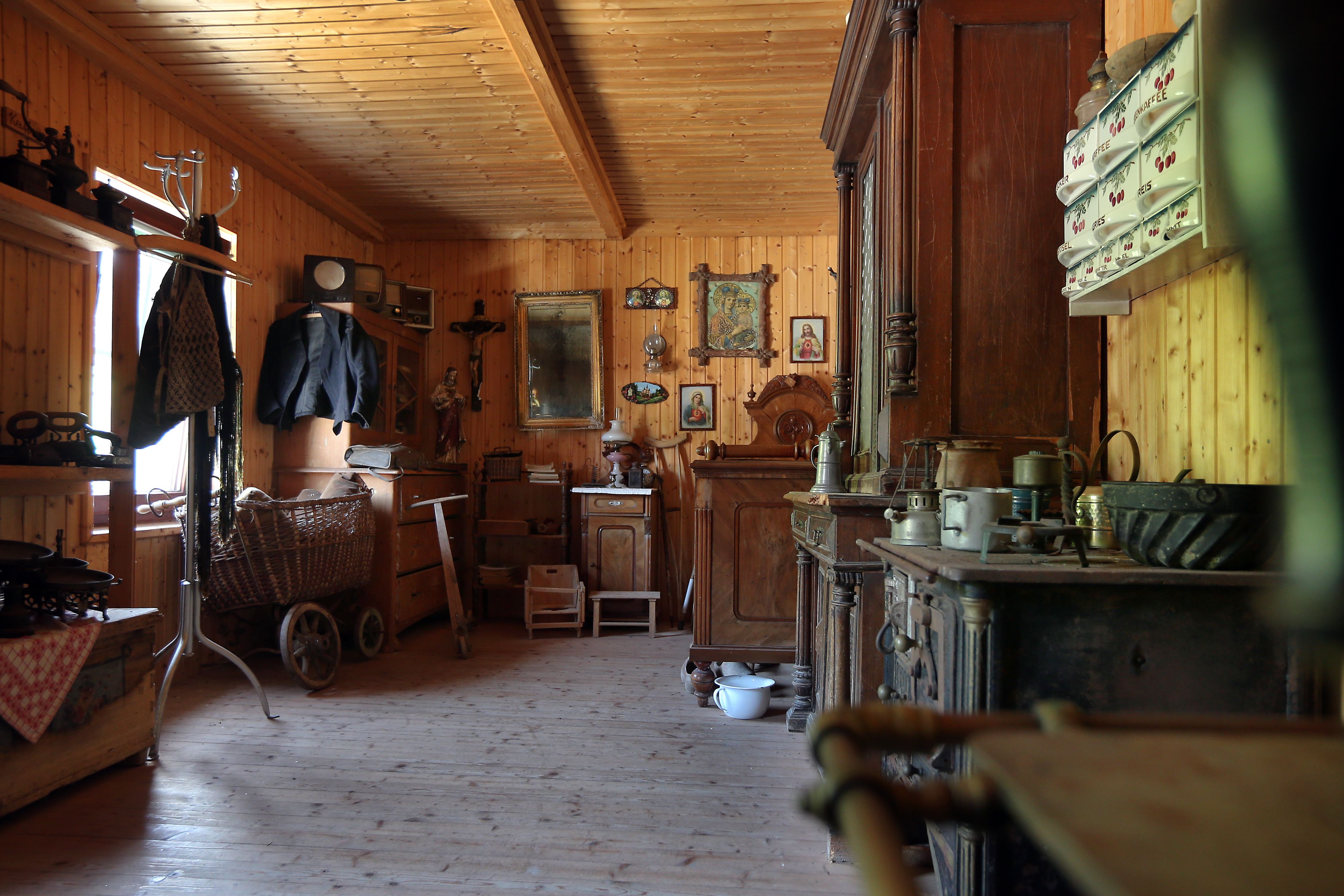 Innenansicht eines traditionellen Bergbauernhauses mit Holzmöbeln und antiken Gegenständen.