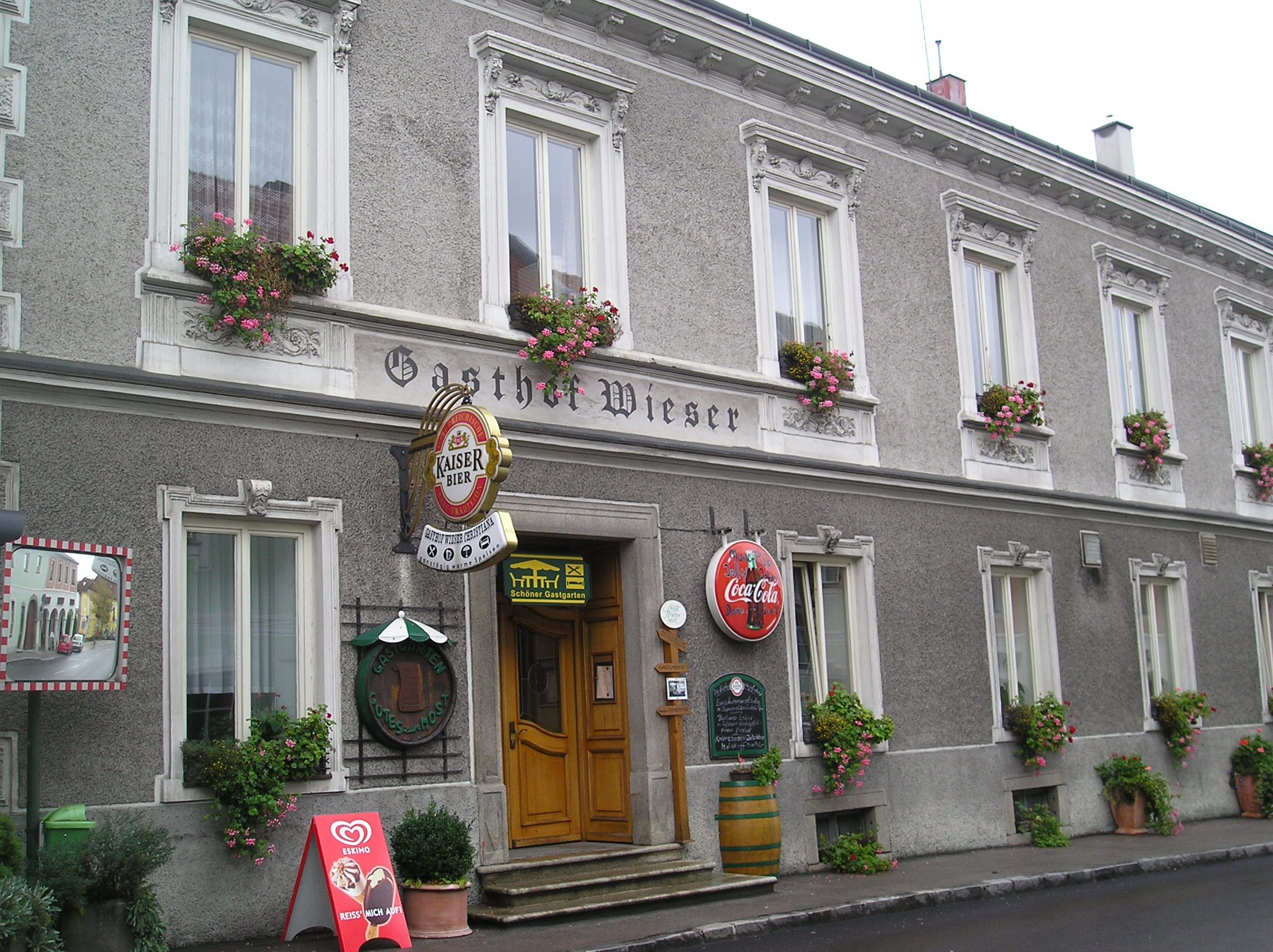 Fassade des Gasthofs Wieser mit Blumenkästen und Werbeschildern.