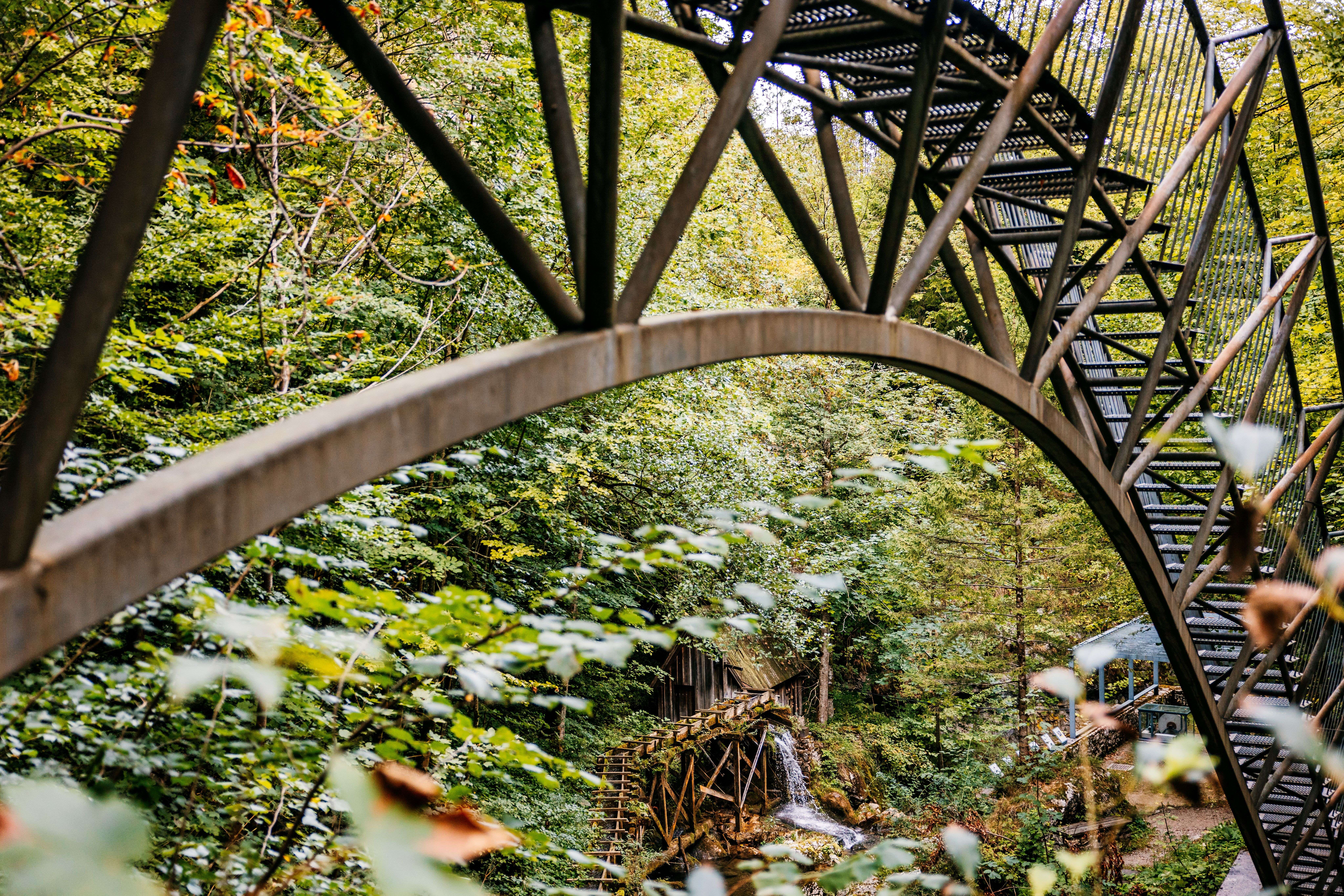 Erlebnisbrücke in Ybbsitz mit geschwungener Stahlkonstruktion und historischem Wasserrad im Hintergrund.