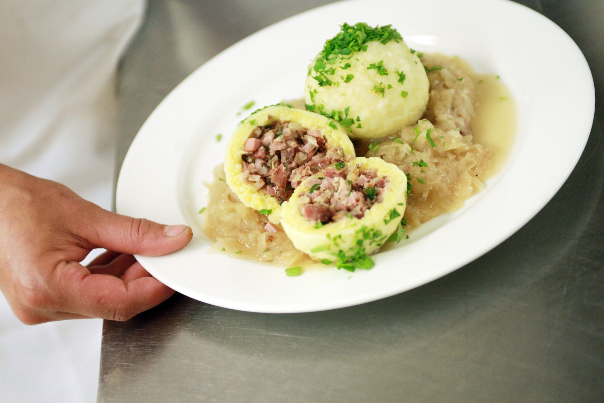 Ein Teller mit gefüllten Knödeln auf Sauerkraut, garniert mit Petersilie.