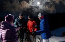 Unter dem sanften Licht des Mondes versammeln sich begeisterte Wanderer, um die winterliche Stille der verschneiten Landschaft zu genießen. Die frische, kalte Luft und das Knirschen des Schnees unter den Schneeschuhen schaffen eine magische Atmosphäre für unvergessliche Erlebnisse in der Natur.