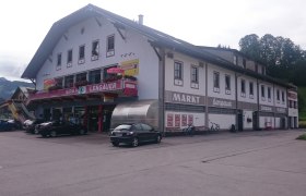 Geb&auml;ude mit Spar-Lengauer-Markt und Post-Partner-Schild, Autos und Fahrr&auml;der davor.