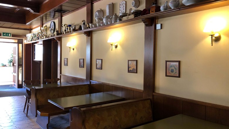 Innenansicht eines traditionellen Gasthauses mit Holzmöbeln und Dekorationen auf einem Regal.