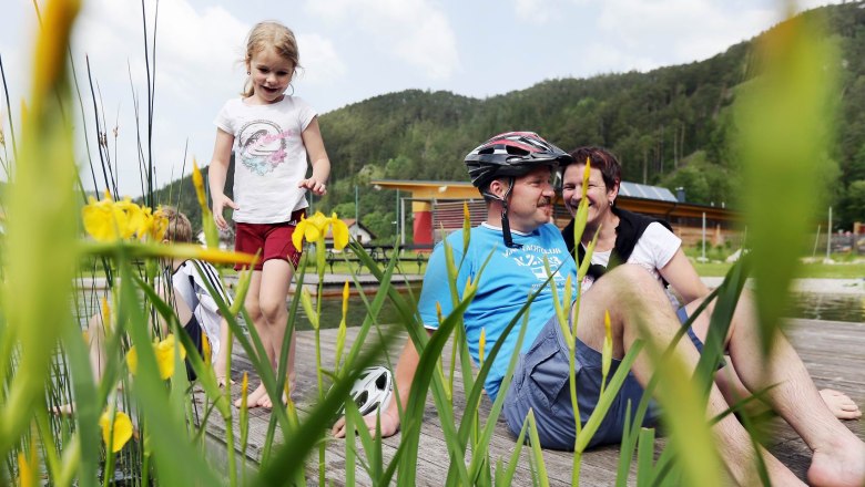 Family relaxing on a jetty at the Türnitz natural adventure pool.