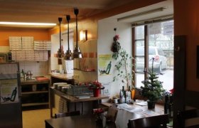 Innenansicht einer Pizzeria mit Tischen, Stühlen und Dekorationen.