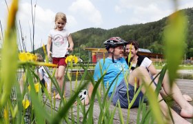 Family relaxing on a jetty at the Türnitz natural adventure pool.