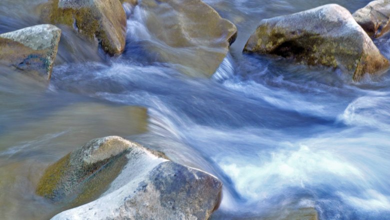 Fließendes Wasser über Steine in einem Bach.