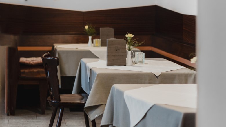 Innenansicht eines gemütlichen Restaurants mit Holzmöbeln und gedeckten Tischen.